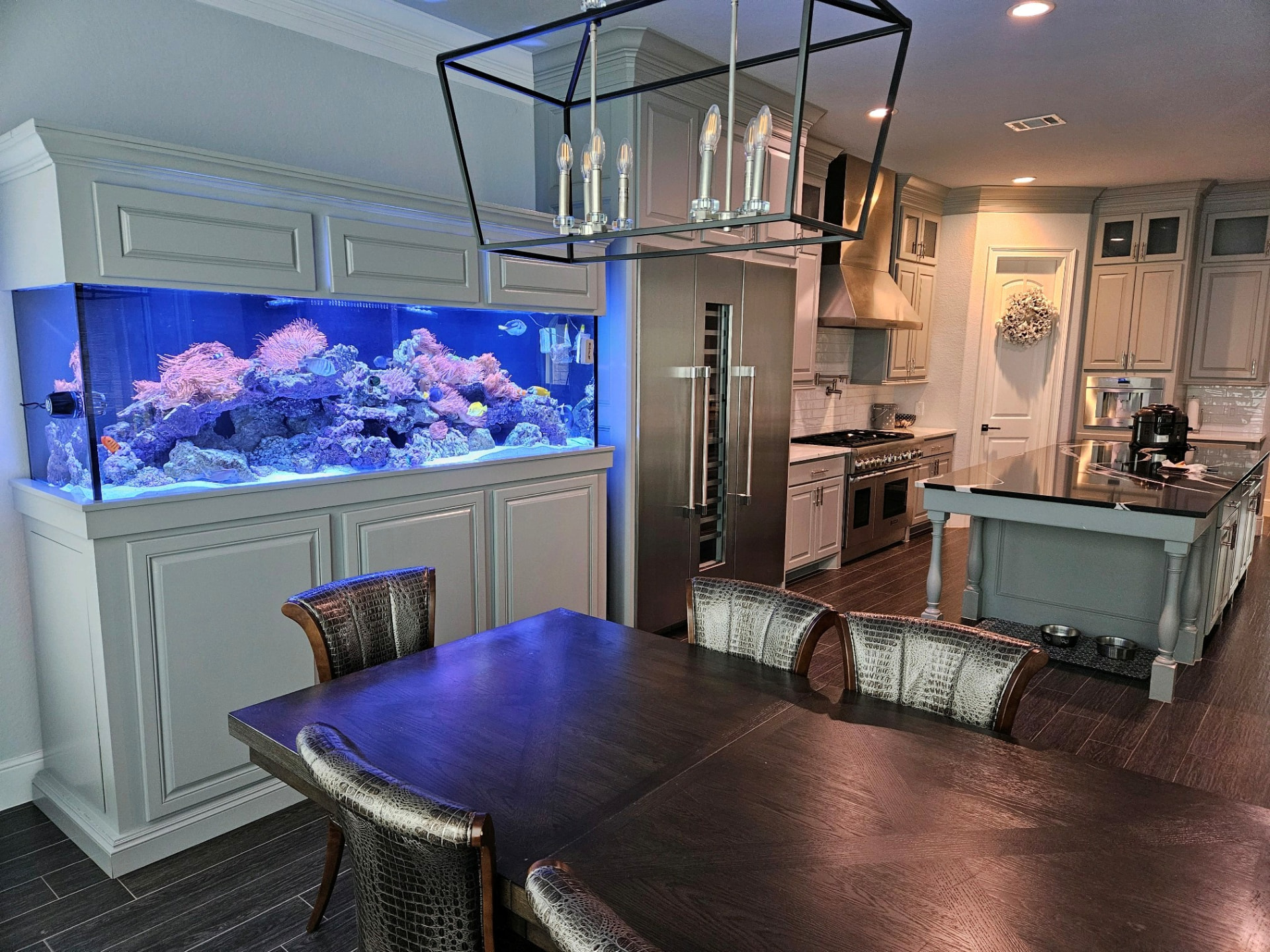 Reef aquarium built into kitchen cabinetry beside a dining table